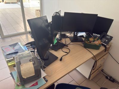 three computer monitors sitting on a desk in front of a window