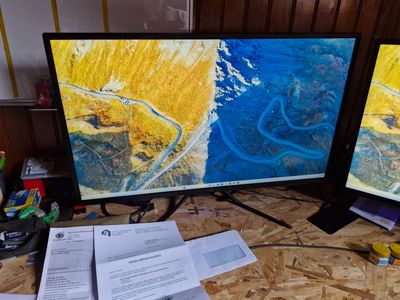deux écrans posés sur une table recouverte de papiers