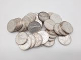 une pile de pièces d'argent empilées les unes sur les autres sur une surface blanche