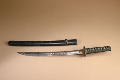 une paire de vieux sabres de samouraï japonais exposés sur un fond beige