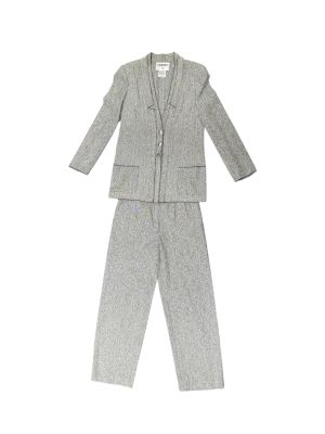 Le costume est gris et se compose d'une chemise à col blanc et d'un pantalon.