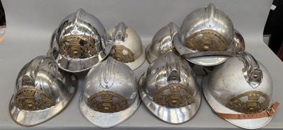 six casques de pompier argentés posés sur une table blanche