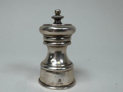 une poivrière en argent posée sur une table blanche