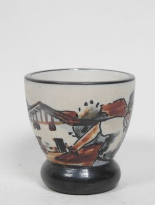 une petite tasse décorée d'une peinture, posée sur une table