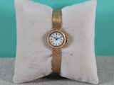 une photo d'une montre en or posée sur un oreiller