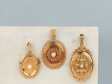 trois boucles d'oreilles en or et un pendentif en perle posés sur un bloc de marbre