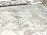 a silver tray with a dragon design on it