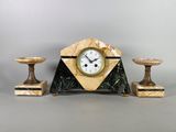 une horloge posée sur une table, à côté de deux bougies