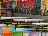 des tables et des chaises aux couleurs vives devant une fresque murale représentant des super-héros