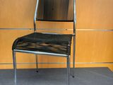 une chaise noire posée devant un mur en bois