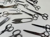 many pairs of scissors sitting on a white surface
