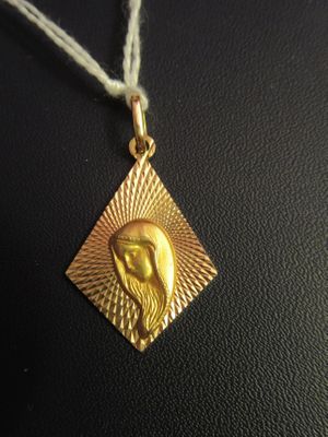 a close up of a gold pendant with a bird on it ' s face