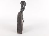 a statue of a woman sitting on top of a piece of wood