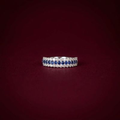 a white gold ring with blue sapphires and diamonds on a red background