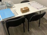 a white table with two black chairs and a brown box on top of it