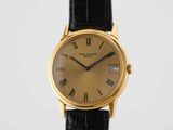 a gold plated wrist watch with roman numerals and black leather strap