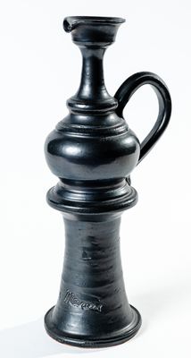 un vase noir posé sur une surface blanche