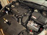 the engine of a car with its hood open and a car battery in the trunk