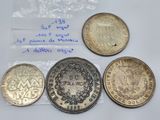 a group of five different coins sitting on top of a white surface