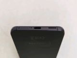 a close up of the back of a black phone on a white surface