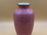 a purple vase with a blue lid sitting on a table