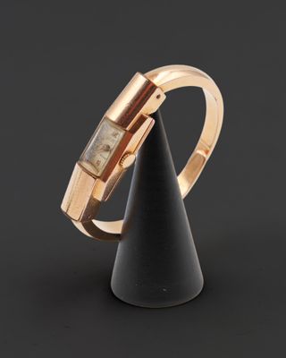un gros plan d'une bague en or ornée d'un cône noir, posée sur une surface noire