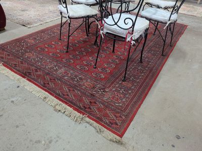 quatre chaises et une table posées sur un tapis rouge