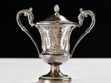 an antique silver plated trophy on a white table with a black background