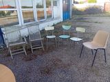 Plusieurs chaises et tables sont disposées en cercle devant un bâtiment.