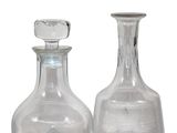 two clear glass bottles sitting next to each other on a table