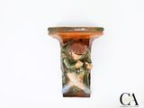 une figurine représentant un garçon tenant un poisson, posée sur une étagère