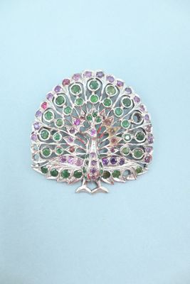 a close up of a brooch with a peacock on it
