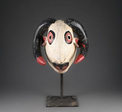 une sculpture en bois représentant une tête de bélier avec des cornes, posée sur un socle