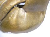 une grande sculpture en bronze représentant une tête d'homme sur un fond blanc