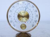 une horloge en or posée sur une table en marbre, avec un mur blanc en arrière-plan