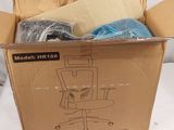 une boîte en carton contenant une chaise et d'autres objets, posée sur une surface blanche