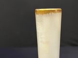 a white vase with a gold rim sitting on a table