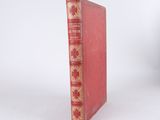 a red book with gold trim sitting on a white surface