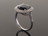 a close up of a black and white diamond ring on a reflective surface