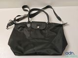 the longchamp bag is black and has a leather handle