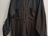 black shirt hanging on a hanger on a wall next to a coat