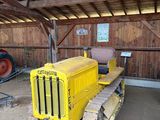 un tracteur jaune dans une grange, avec un autre tracteur derrière lui