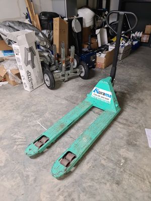 un chariot élévateur garé dans un garage, à côté d'une pile de cartons
