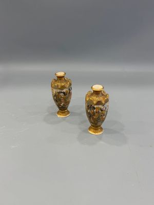 two gold vases sitting on top of a table next to each other