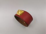 un gros plan sur un bracelet en cuir rouge orné de pyramides dorées
