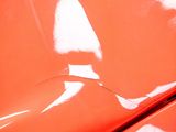 close up of a red car ' s hood with a reflection of a person on the hood
