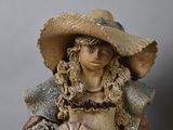 a figurine of a woman wearing a hat and holding a dog