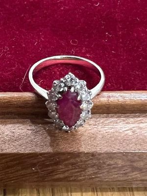 une bague ovale sertie d'un rubis et de diamants, posée sur un fond de velours rouge
