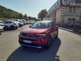 Le SUV rouge est garé devant un immeuble devant lequel sont garées des voitures.