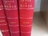 Trois livres rouges sont empilés sur une étagère d'une bibliothèque